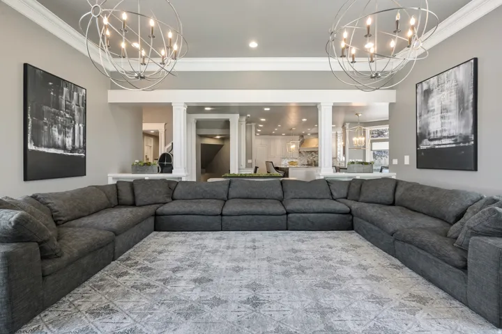 Spacious living area featuring dual orb chandeliers and a light grey color palette