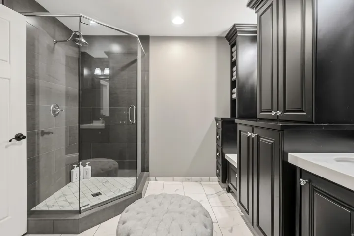 Frameless glass shower enclosure with dark gray tile surround and chrome fixtures