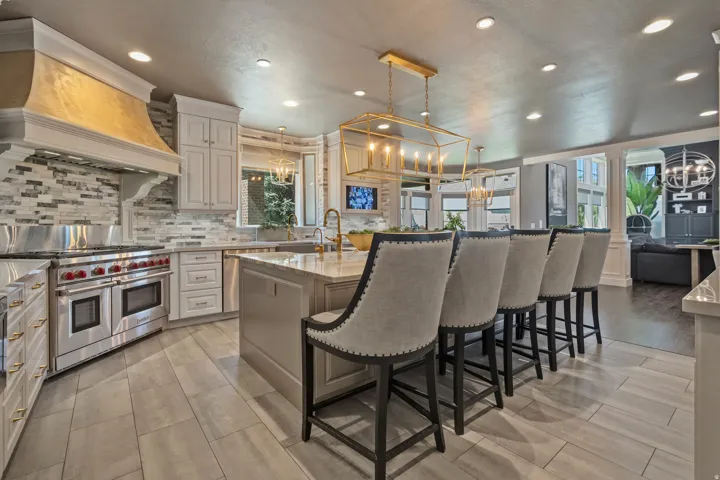 Gourmet kitchen featuring a professional-grade stainless steel range, custom range hood, mosaic tile backsplash, light wood-finish flooring, and a large central island with seating