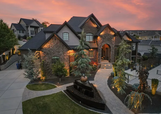 Stone and stucco exterior featuring a grand arched entry and a multi-level roofline