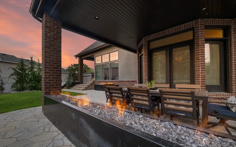 Covered patio featuring a linear fire pit with decorative stones