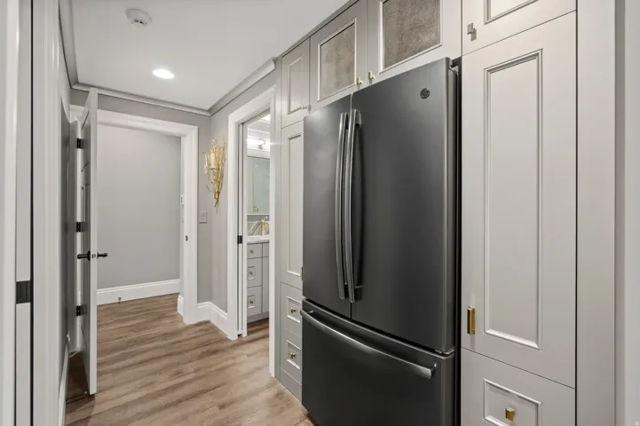 Integrated stainless steel refrigerator framed by custom cabinetry with gold-toned hardware