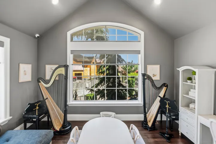 Spacious room featuring vaulted ceilings, rich wood-finish flooring, and gray painted walls