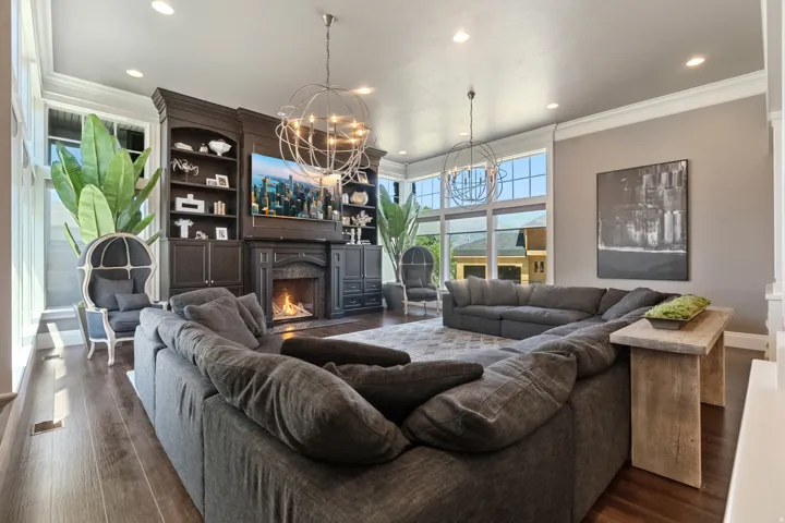 Spacious living area featuring expansive windows, wood-finish flooring, recessed lighting, and a built-in media center with a fireplace