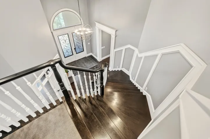 Grand entryway featuring a double staircase with dark wood-finish treads and white balusters