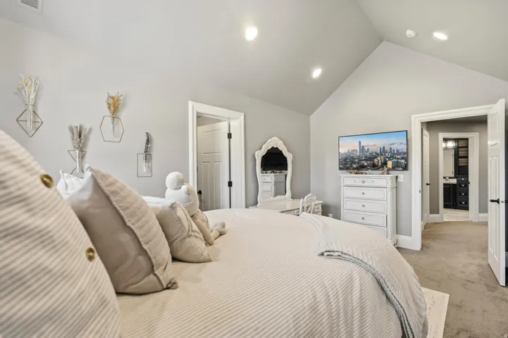 Vaulted ceiling room featuring recessed lighting, a built-in dresser, and an open doorway leading to a bathroom with dark cabinetry