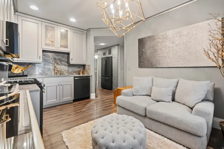 Integrated kitchen and living area featuring wood-finish flooring, recessed lighting, and a geometric chandelier