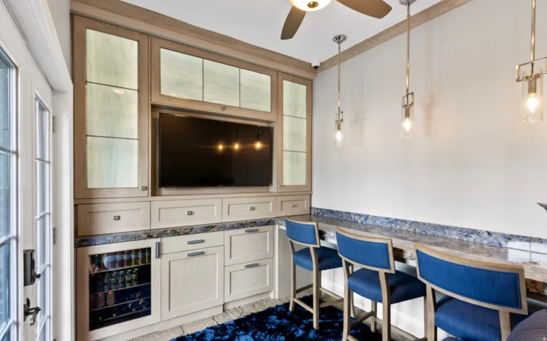 Built-in cabinetry with integrated television, illuminated upper display cabinets, and under-counter beverage cooler