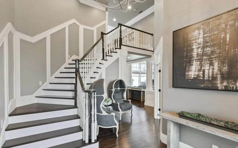 Grand entryway featuring a double staircase with dark treads and white risers, framed by a matching white baluster and dark wood handrail
