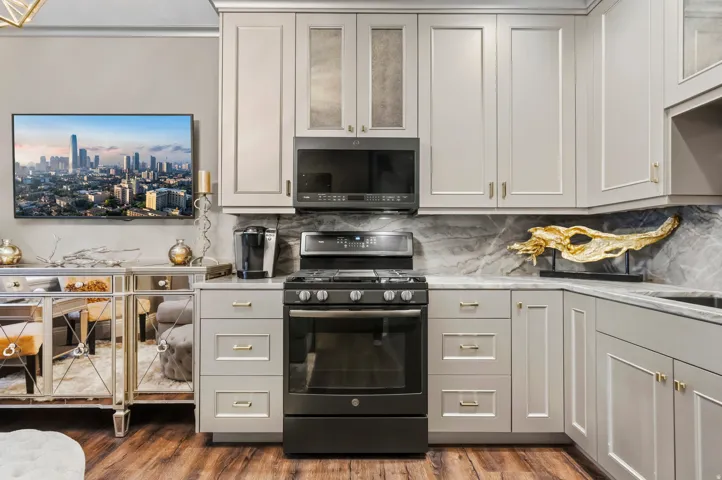 Contemporary kitchen featuring light-toned cabinetry with gold-toned hardware, a matte black range, and a built-in microwave