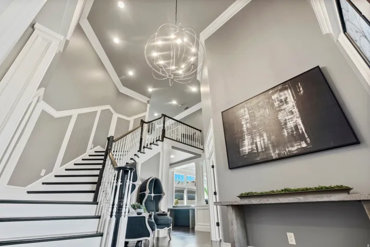 Two-story entryway featuring a grand staircase with dark treads and white risers, an open spindle balustrade, and a dark wood handrail