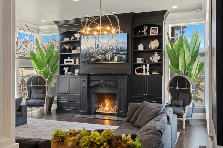 Built-in media center featuring dark cabinetry, integrated shelving, and a central fireplace with a dark stone surround