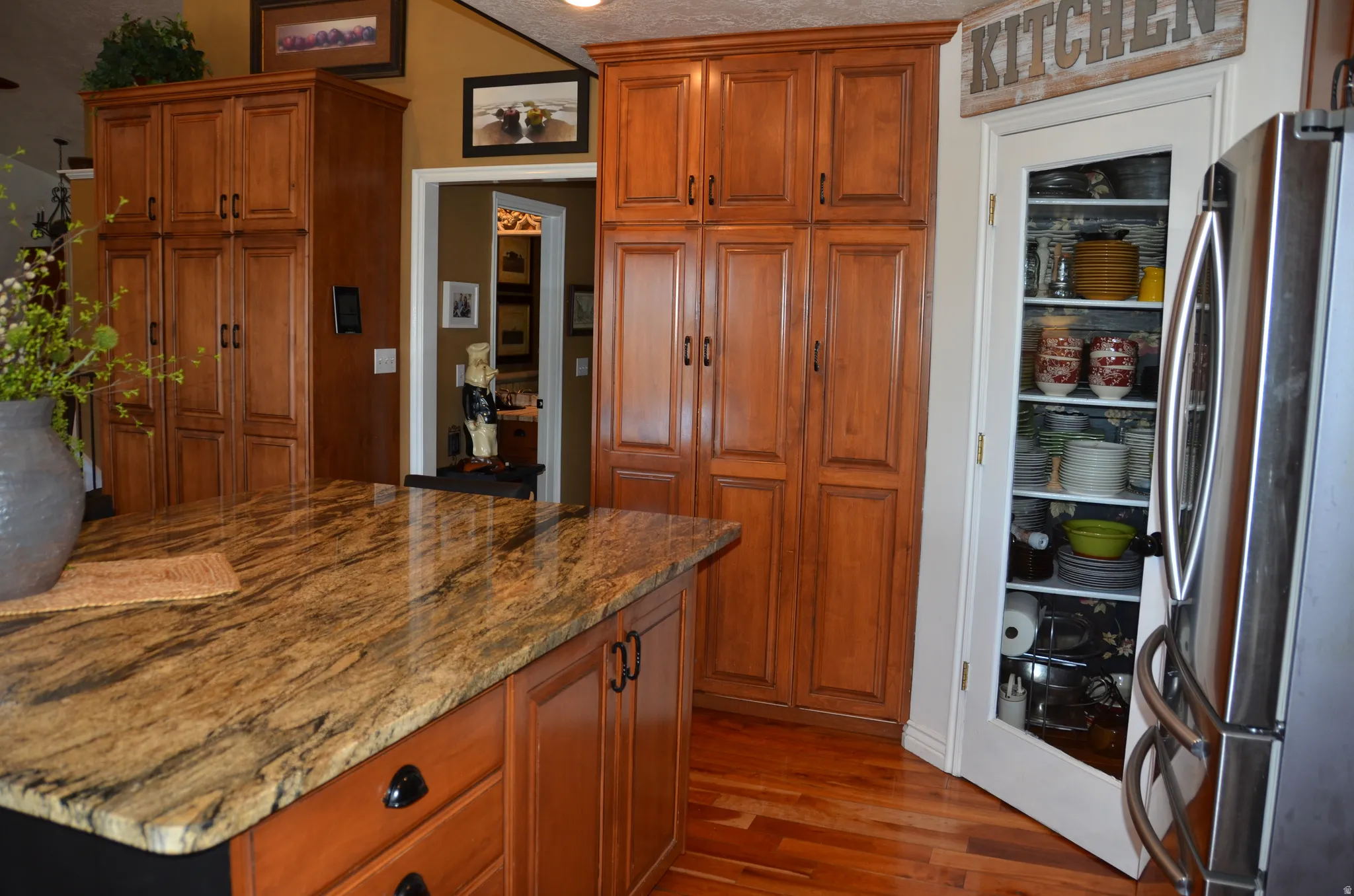 Kitchen featuring a spacious island with a natural stone countertop and rich wood-finish cabinetry