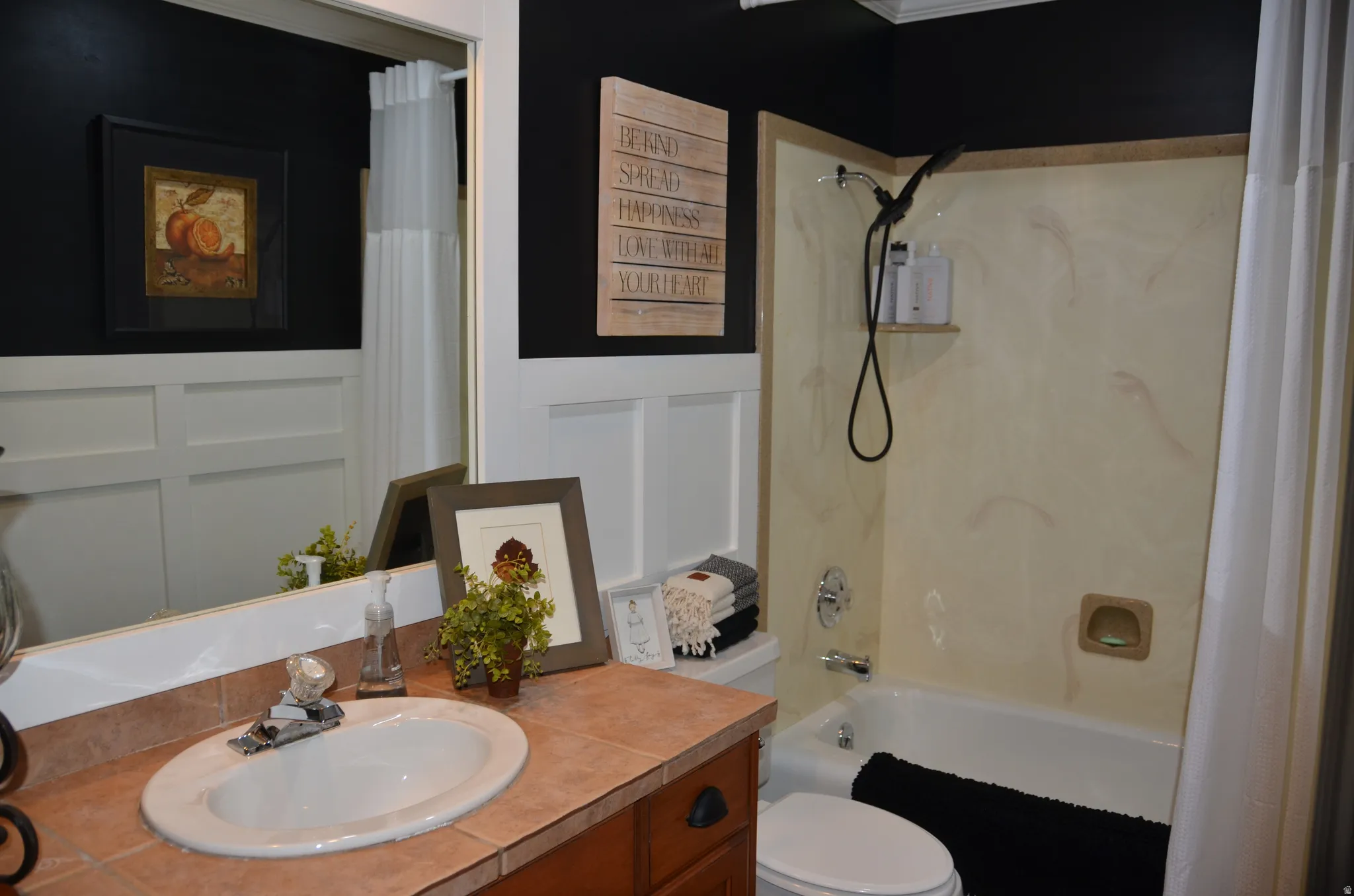 Bathroom featuring a wood vanity with an oval sink, ceramic tile countertop, and a full-width mirror