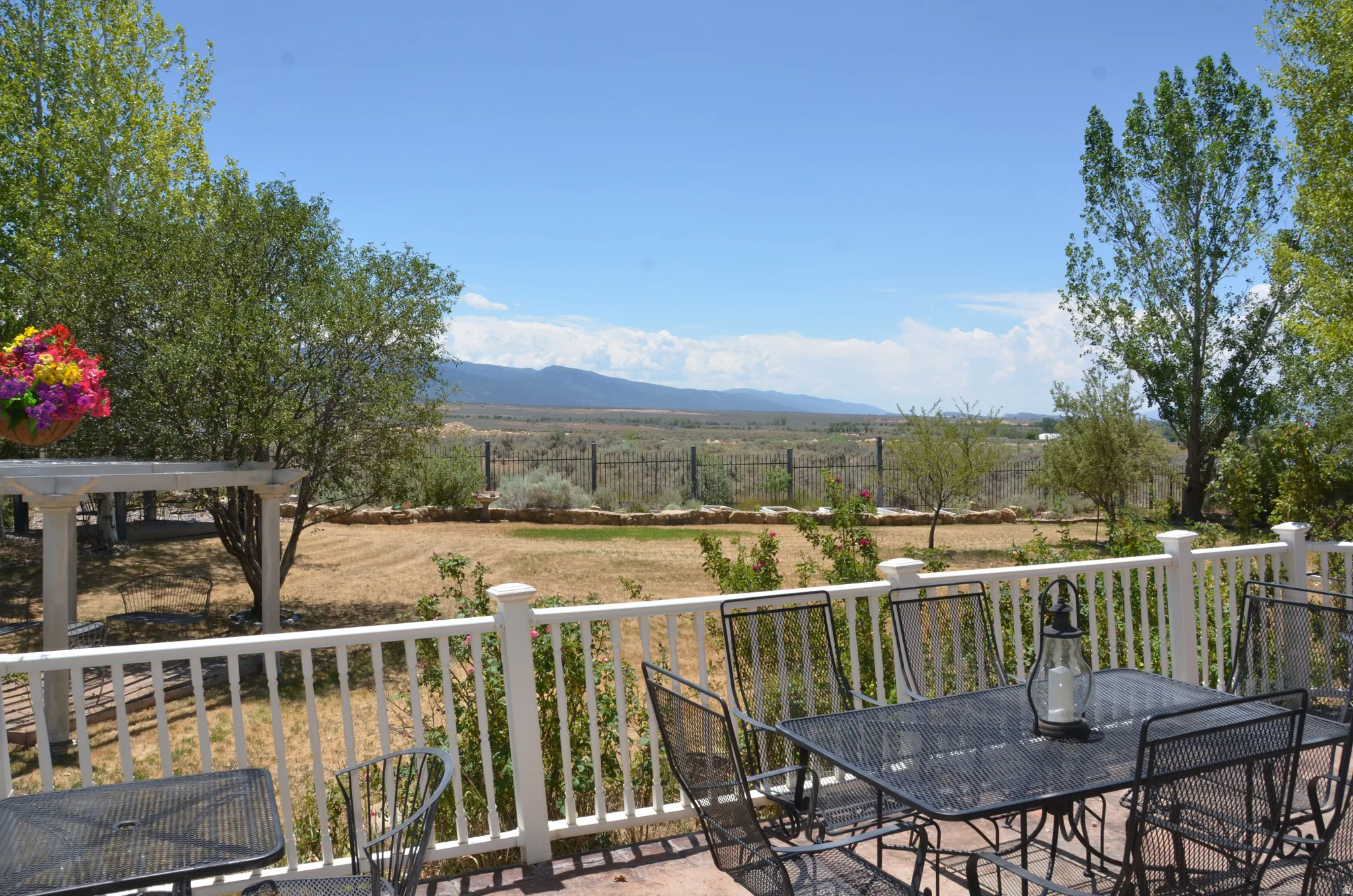 Expansive outdoor patio featuring a white baluster railing and a pergola structure