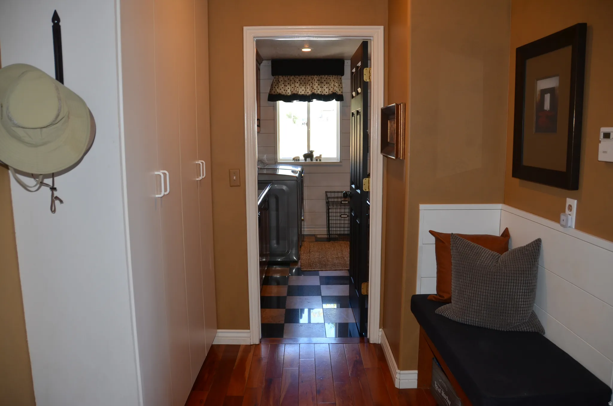 Hardwood flooring extending to a built-in bench with storage, complemented by wall paneling and extensive built-in cabinetry