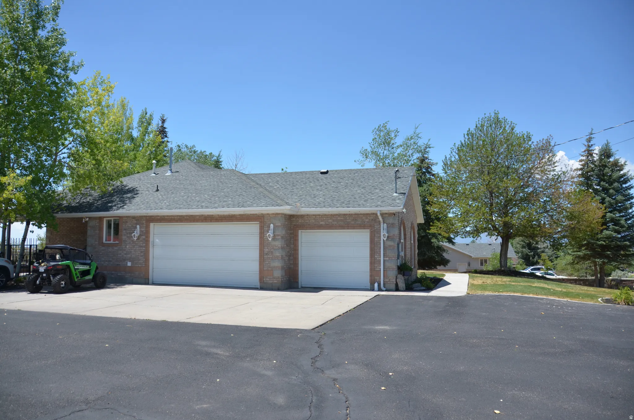 Exterior featuring a three-car garage with white doors, brick facade, and a shingle roof
