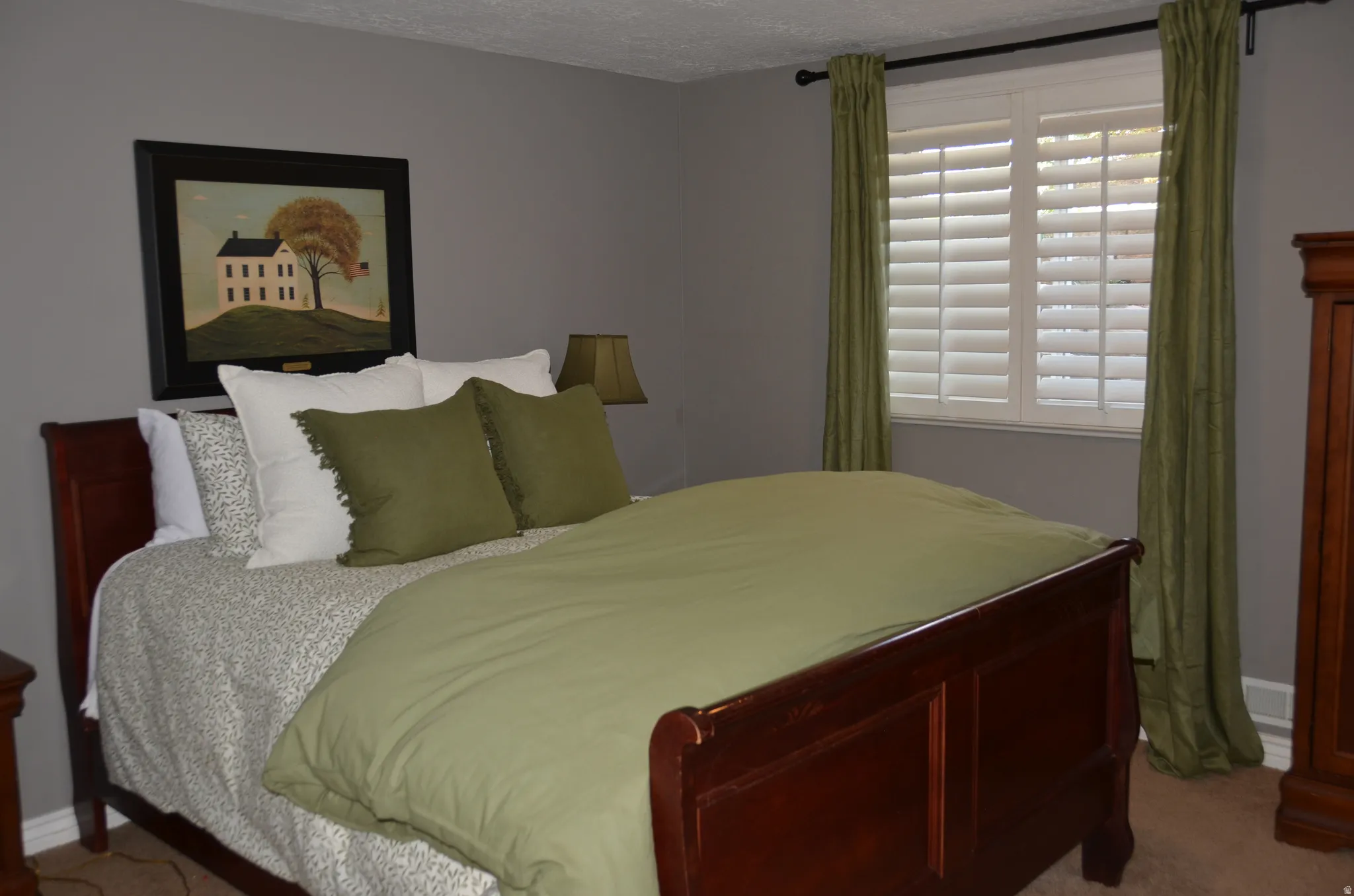 Bedroom featuring a dark wood sleigh bed, light gray wall paint, and white window shutters