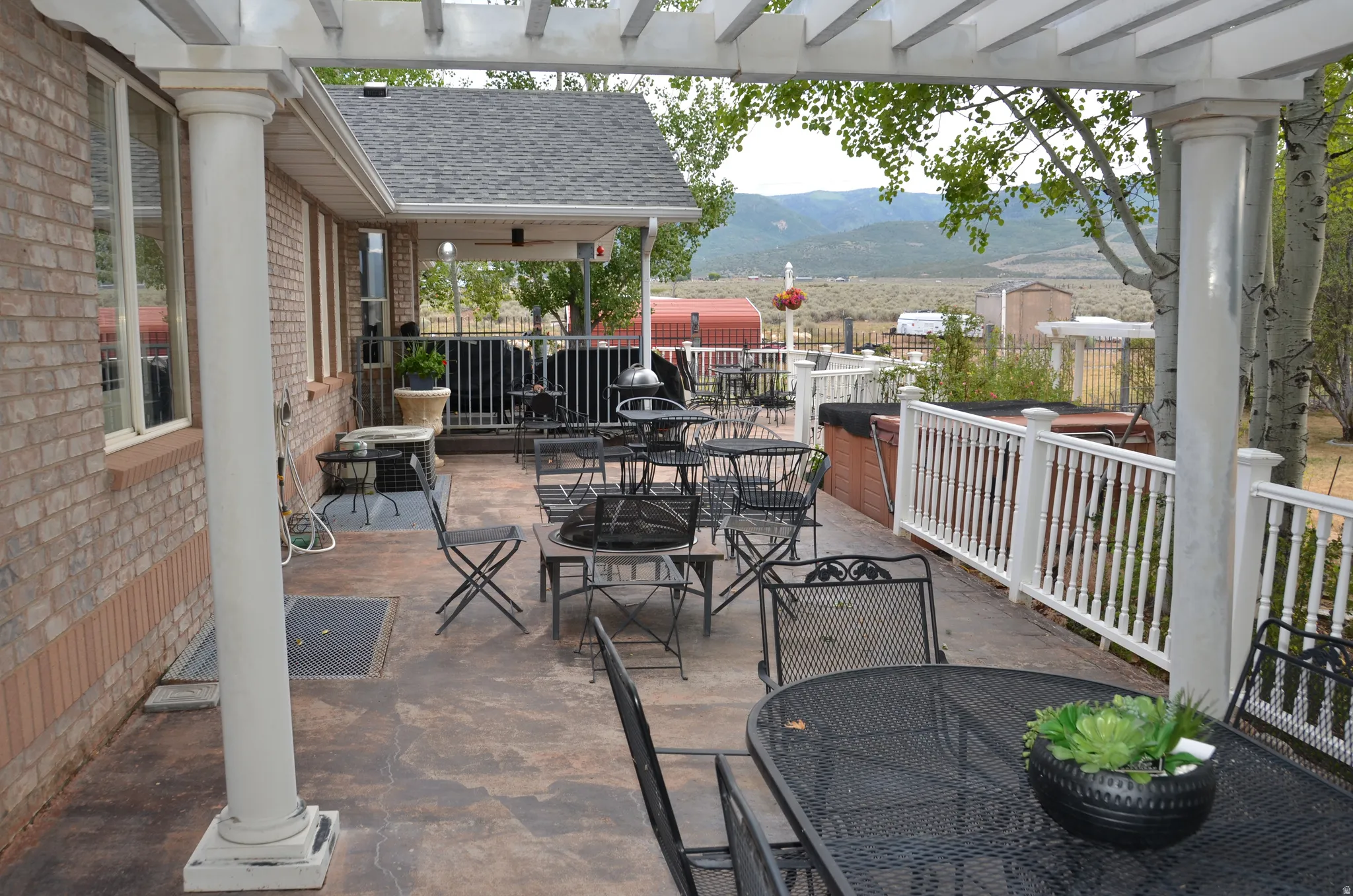 Expansive outdoor patio featuring a pergola, brick siding, and a white railing system