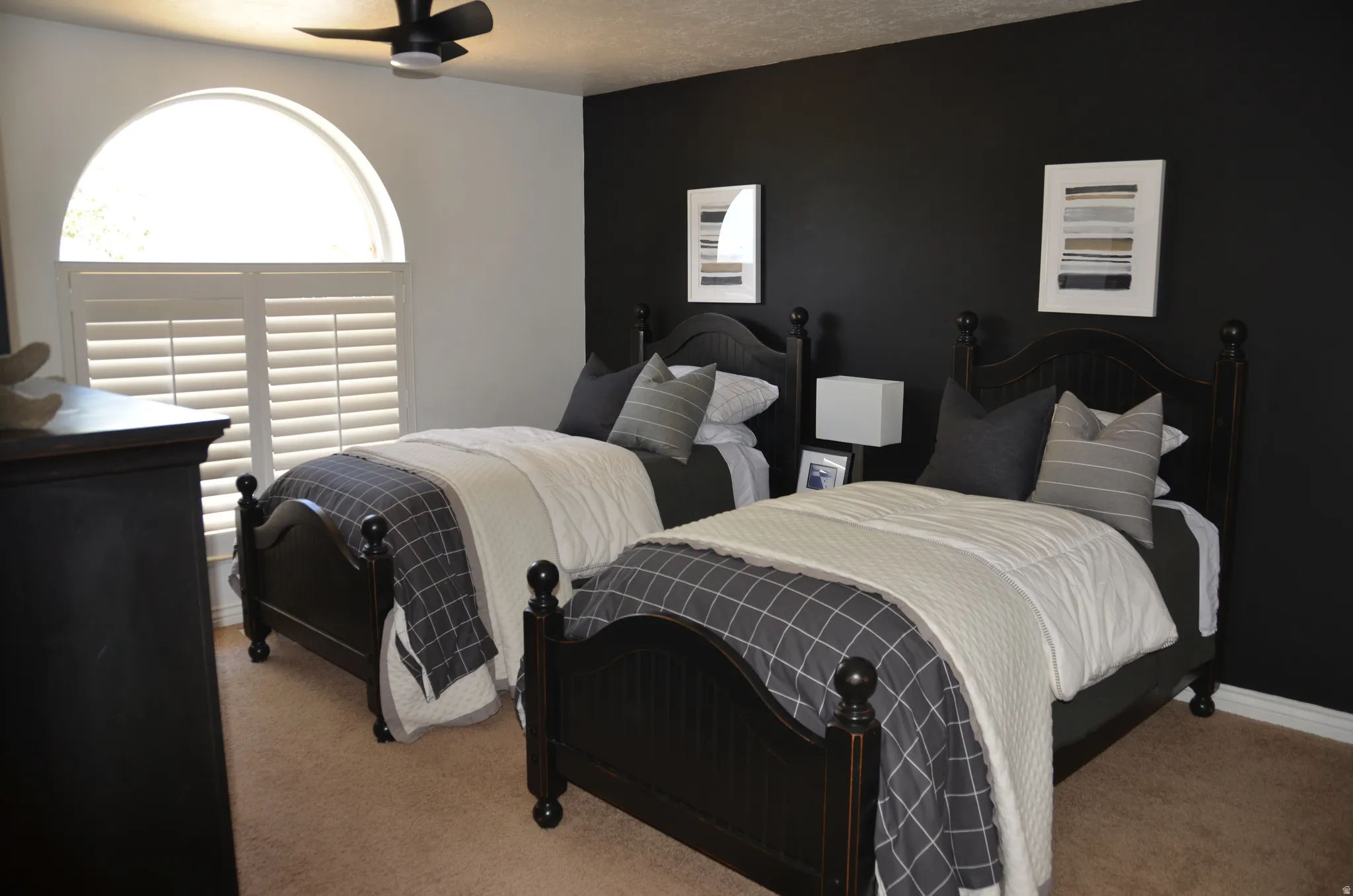 Bedroom featuring an arched window with plantation shutters, a ceiling fan with integrated lighting, and plush carpet flooring