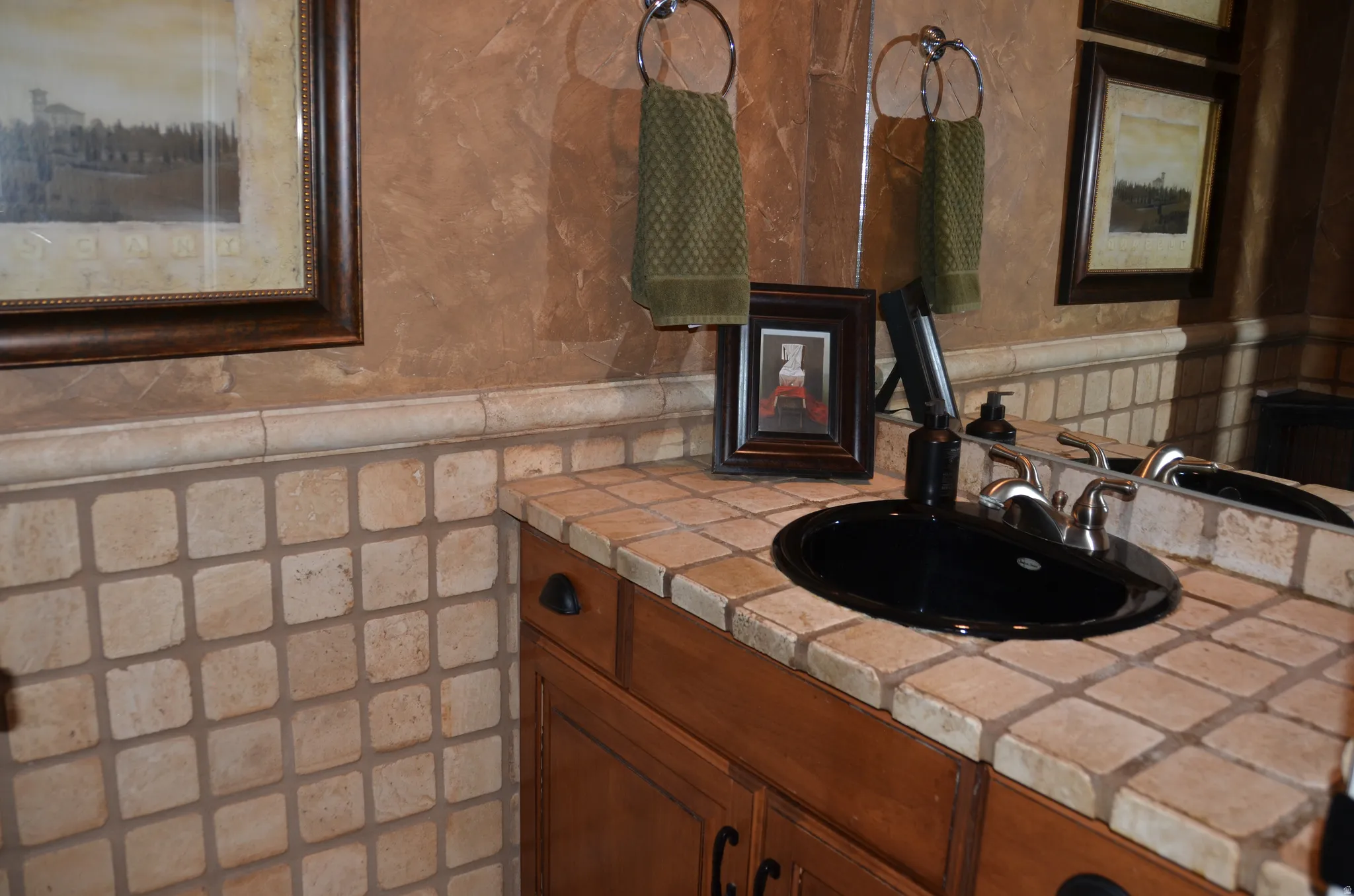 Vanity featuring a black oval sink, brushed nickel faucet, and a tiled countertop