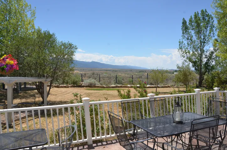 Expansive outdoor patio featuring a white baluster railing and a pergola structure