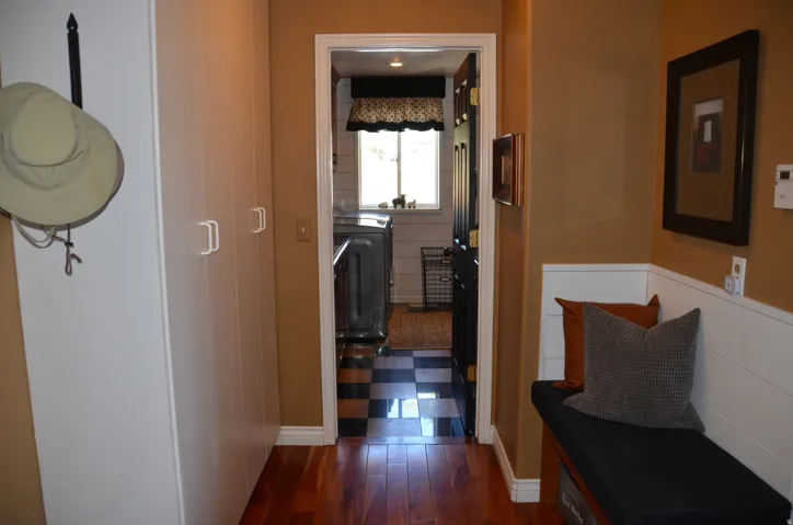 Hardwood flooring extending to a built-in bench with storage, complemented by wall paneling and extensive built-in cabinetry