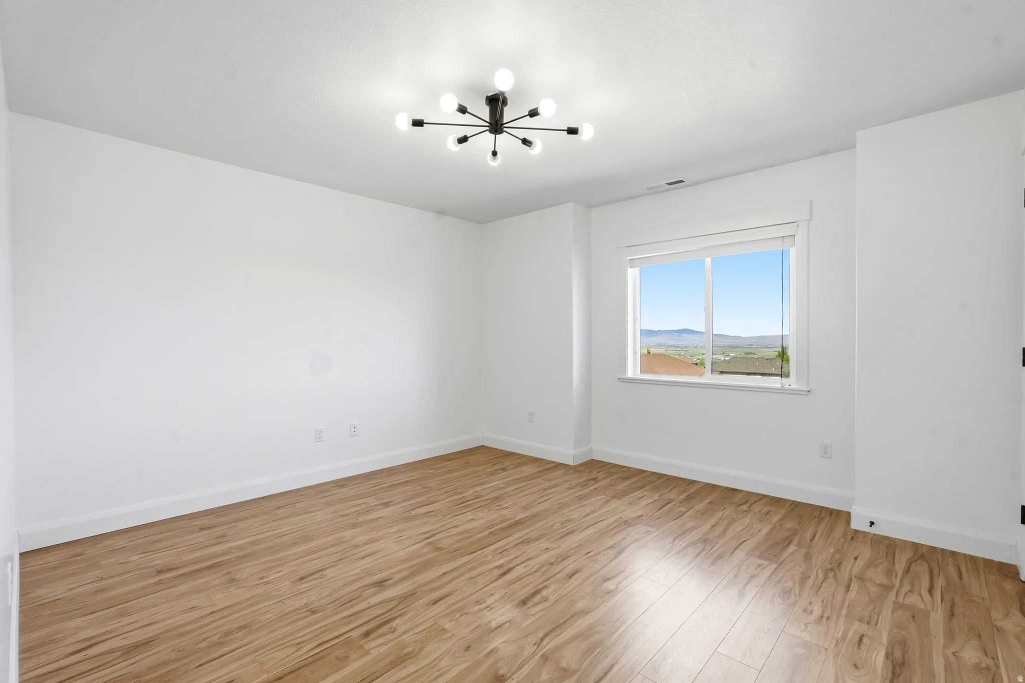 Open room featuring wood-finish flooring and white baseboards