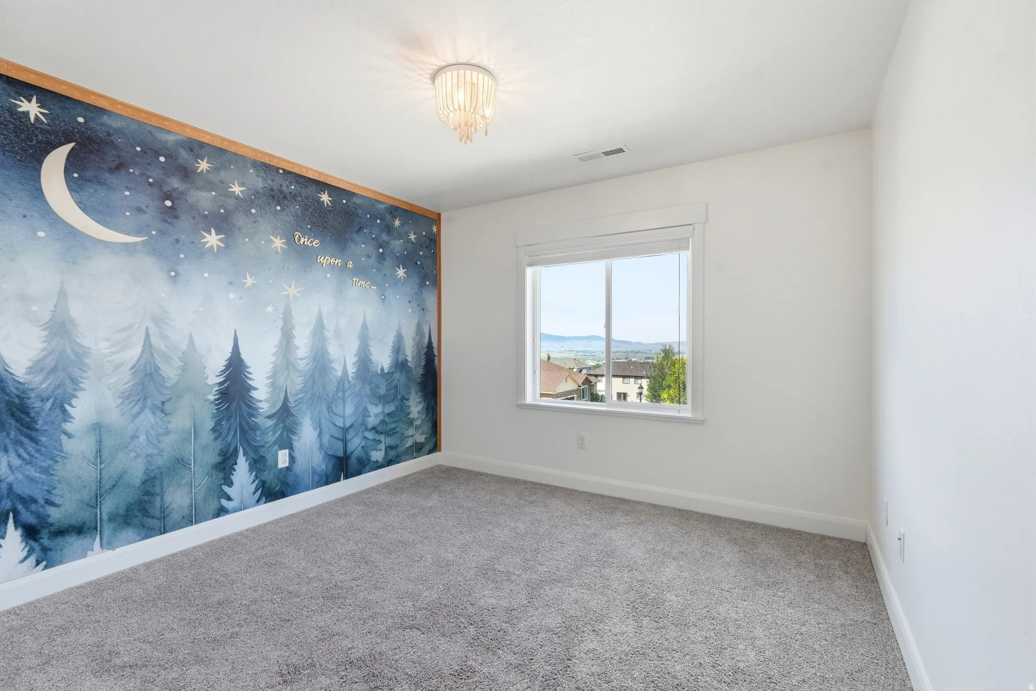 Accent wall featuring a whimsical forest and night sky mural with wood trim