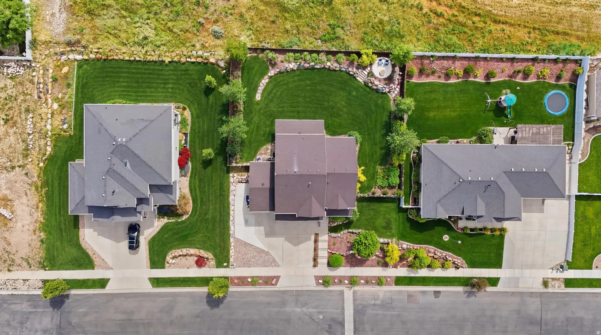 Expansive property featuring a meticulously maintained lawn, mature landscaping, paved driveway, and established fencing