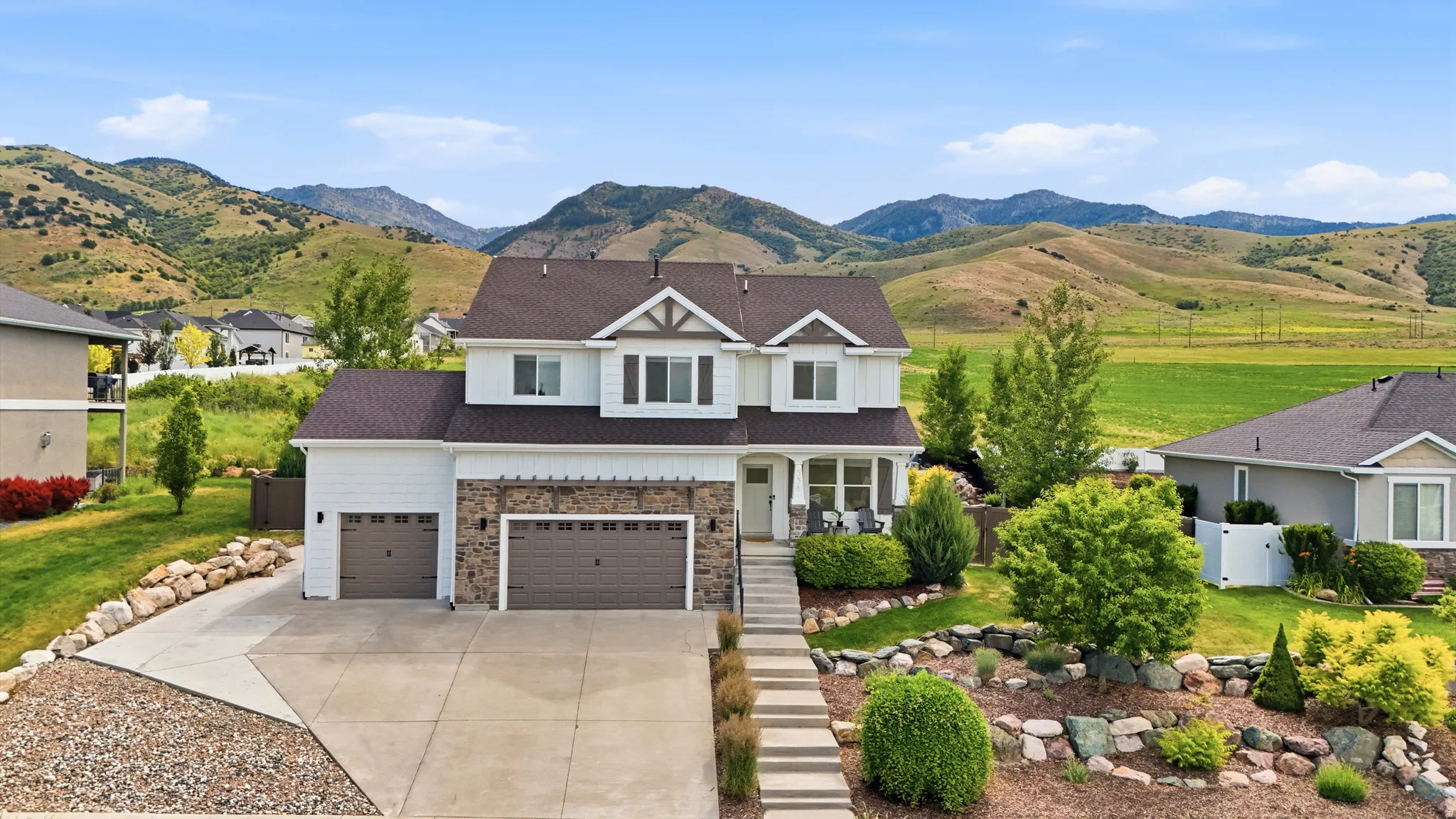 Two-story residence featuring a white siding exterior with stone accents and a dark roof