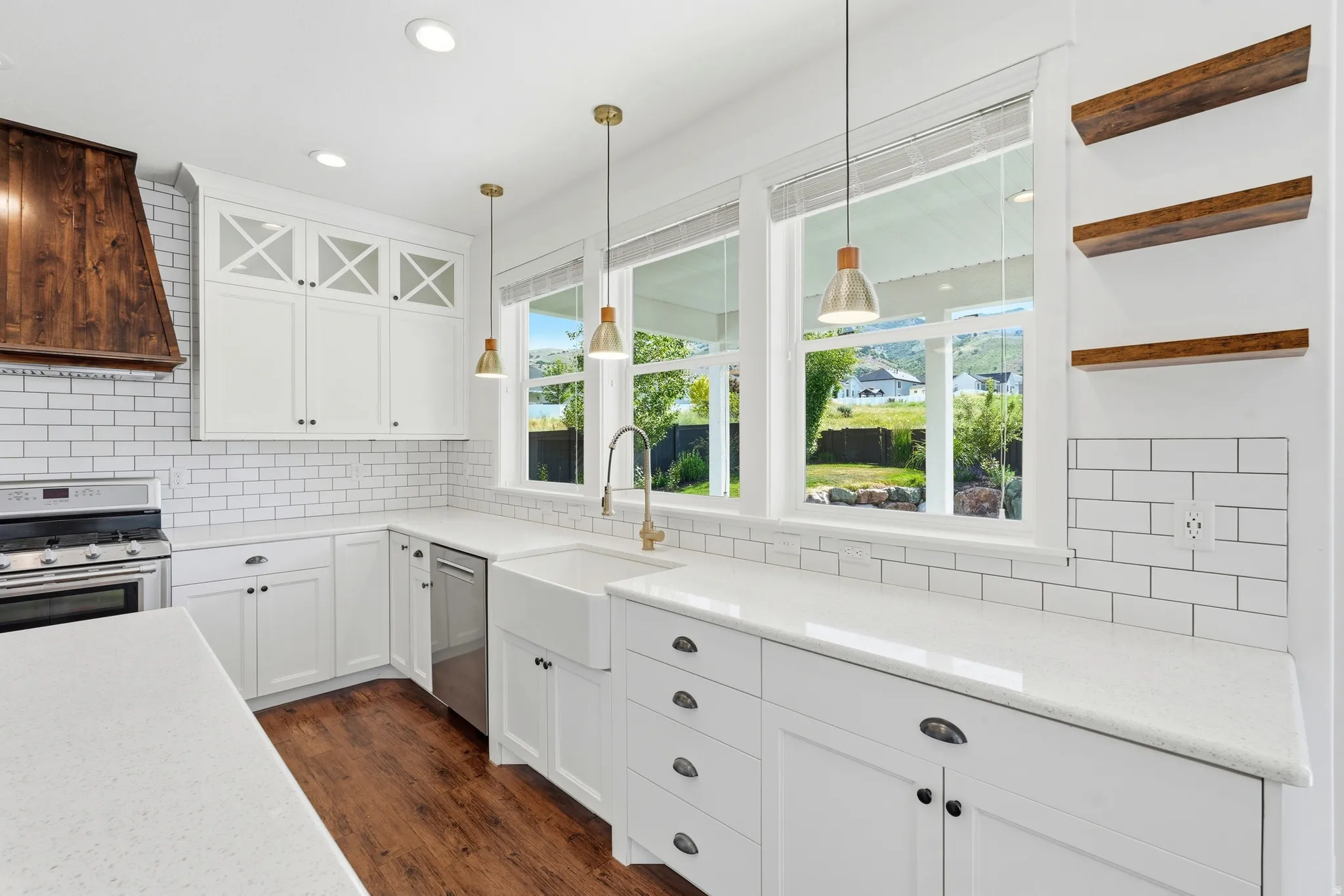 Bright kitchen featuring white cabinetry, quartz countertops, subway tile backsplash, and wood-finish flooring