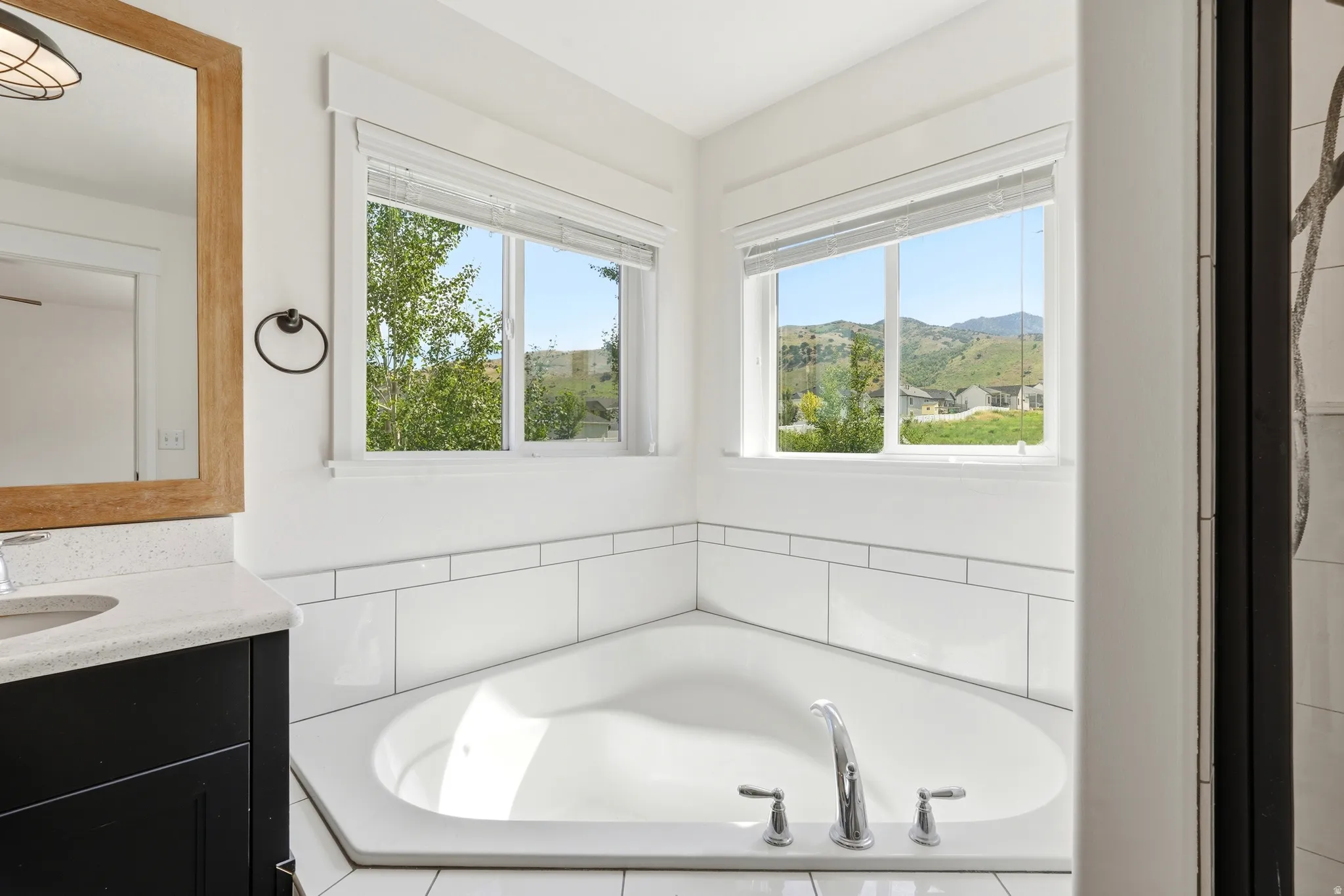 Corner soaking tub with chrome fixtures, surrounded by white subway tile