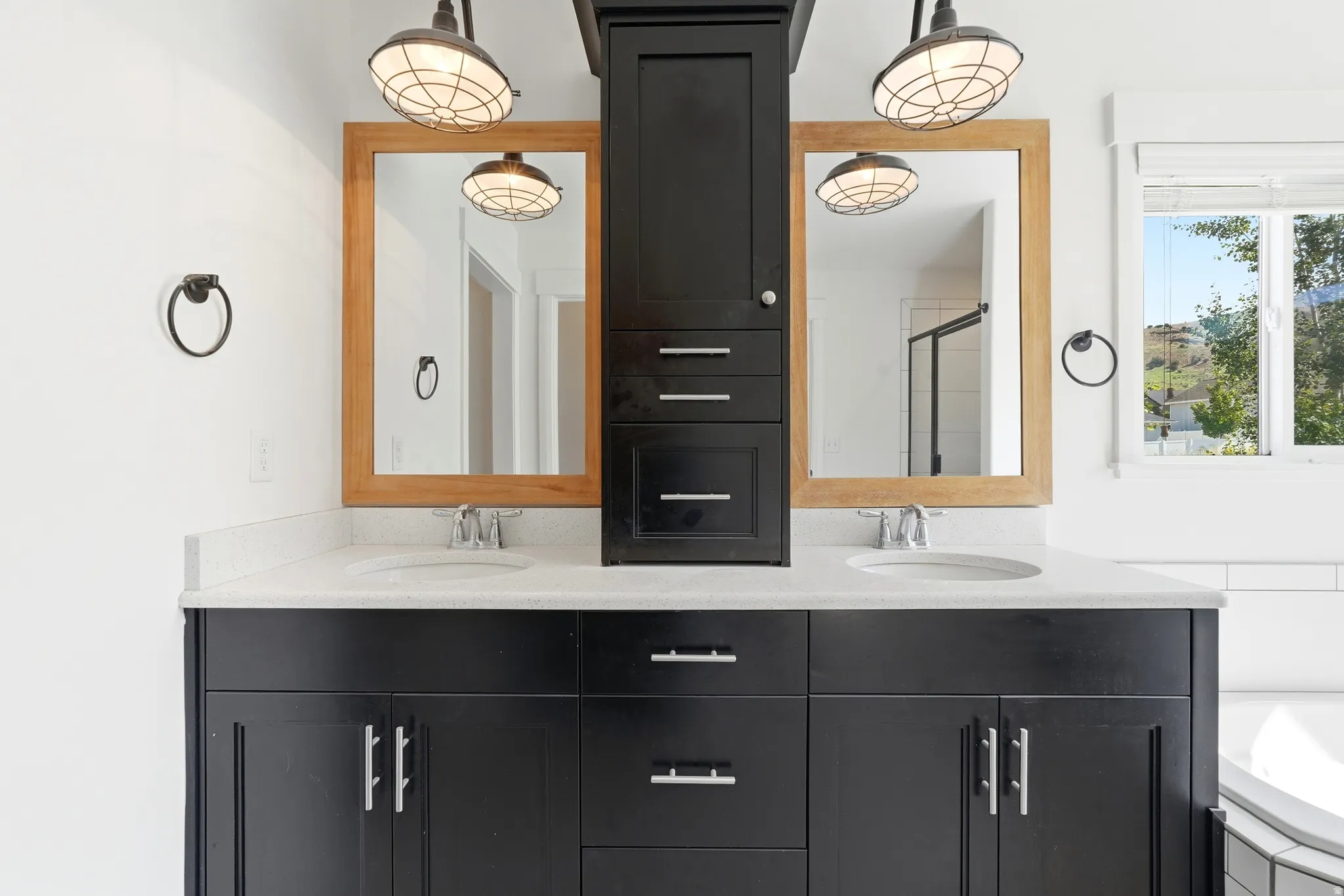 Double vanity featuring black cabinetry, light-toned countertops, dual undermount sinks, and two wooden-framed mirrors