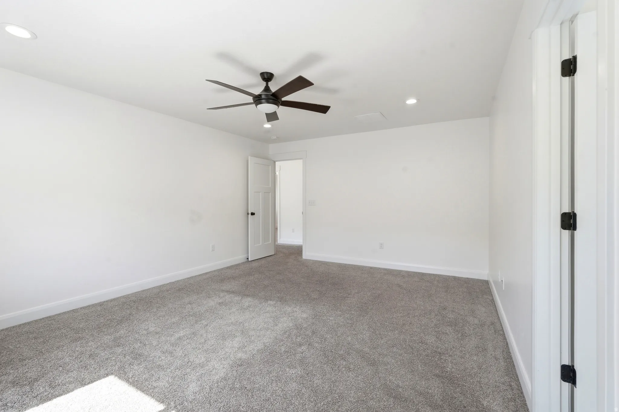 Spacious room featuring neutral carpeting, a ceiling fan with integrated lighting, and recessed lighting fixtures