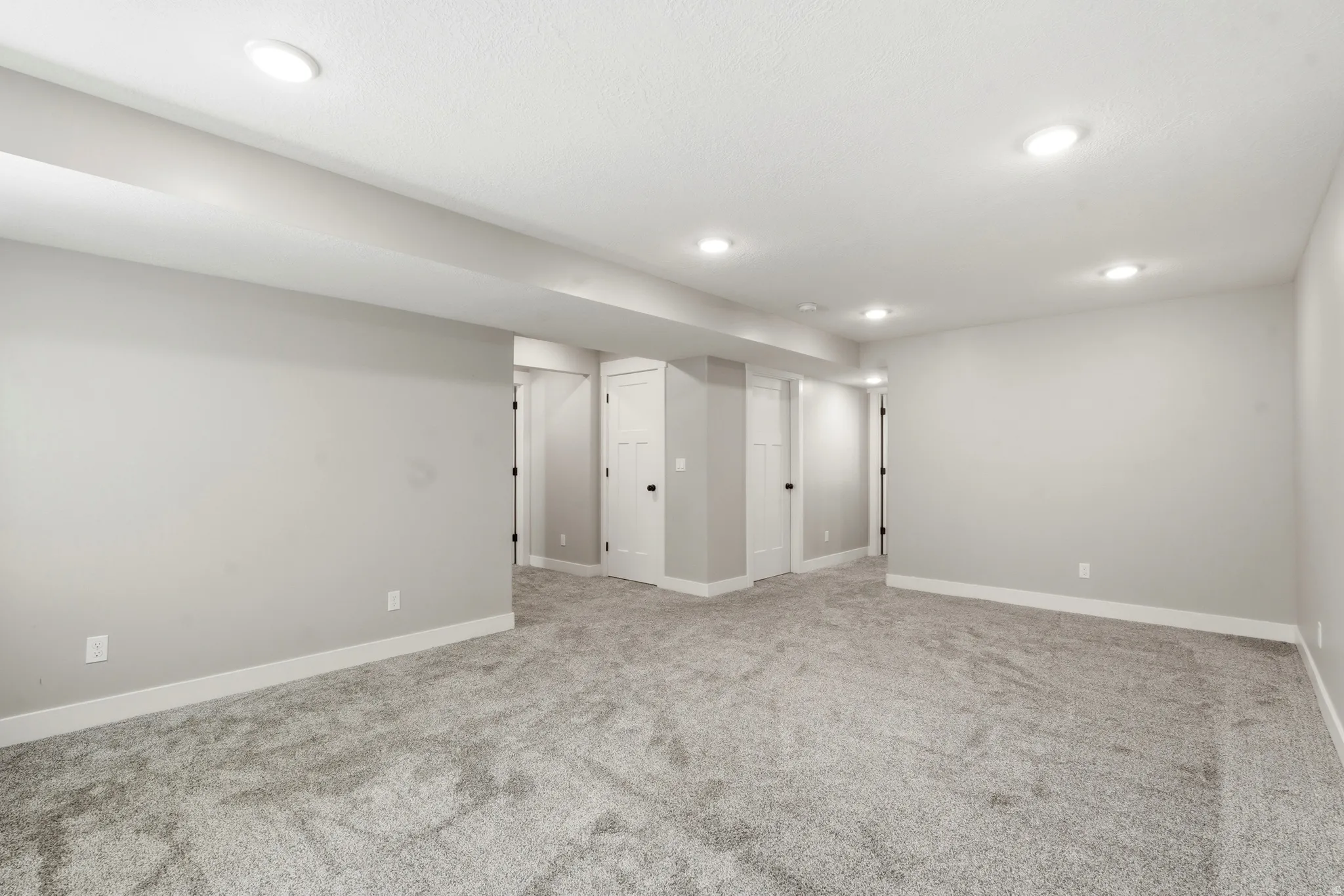 Open room featuring recessed lighting, light gray wall paint, white baseboards, and gray carpeting