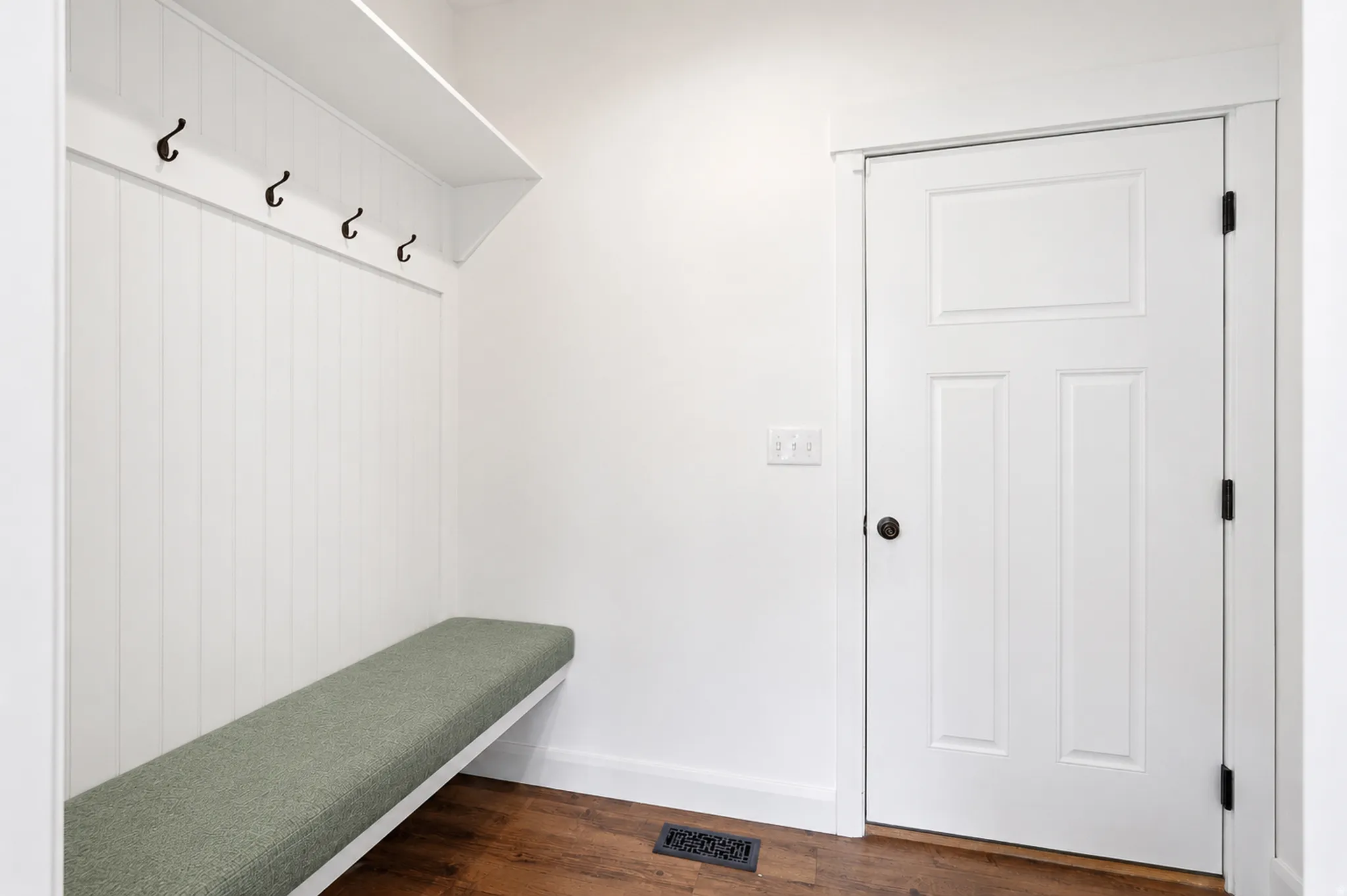 Built-in hall tree with a cushioned bench, five dark-finish coat hooks, and an overhead shelf