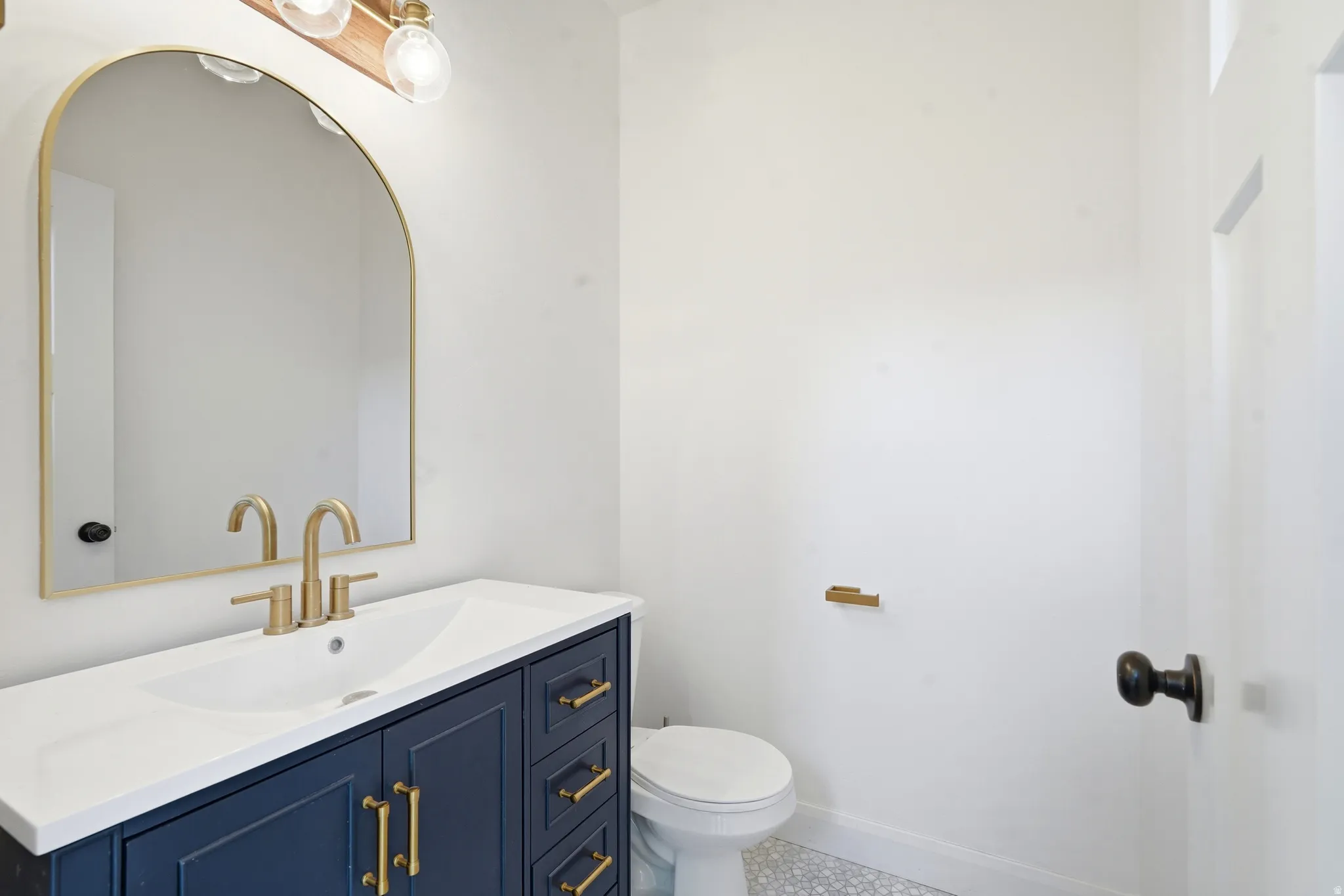 Bathroom vanity featuring a navy base, gold-tone hardware, and a white countertop with an integrated sink