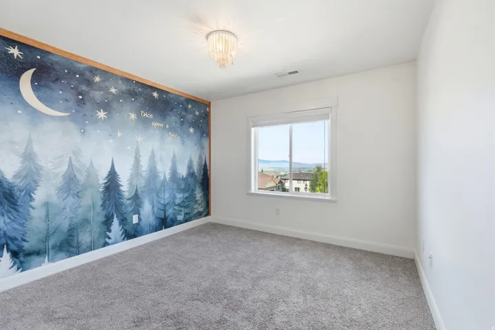 Accent wall featuring a whimsical forest and night sky mural with wood trim