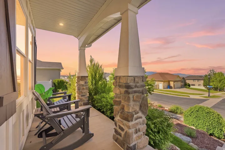 Expansive covered porch featuring stone-clad columns, recessed lighting, and a concrete surface