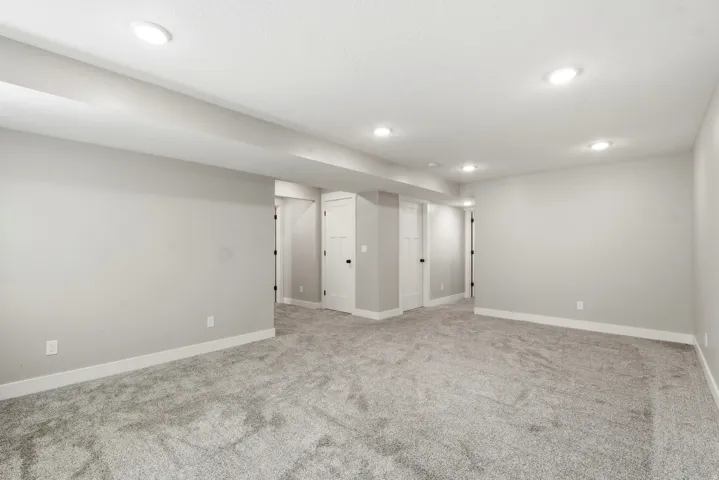 Open room featuring recessed lighting, light gray wall paint, white baseboards, and gray carpeting