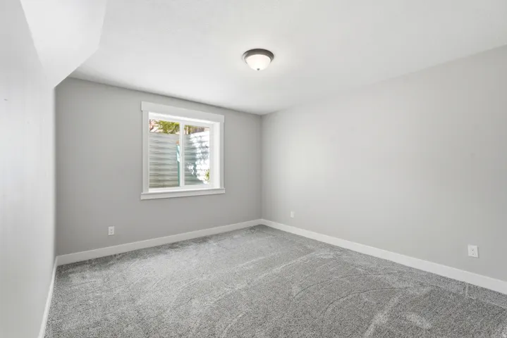 Room featuring light grey wall paint, plush grey carpeting, white baseboards, and a white-framed window