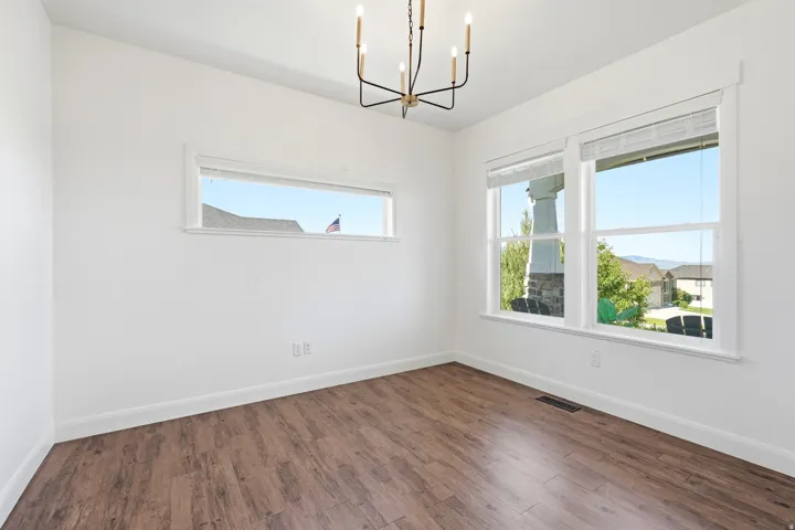 Spacious room featuring wood-finish flooring, white baseboards, and white walls