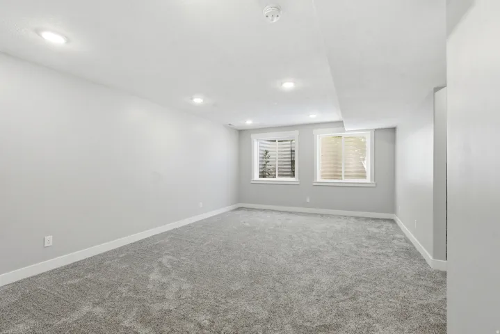 Spacious room featuring neutral gray walls, gray carpeting, and recessed lighting