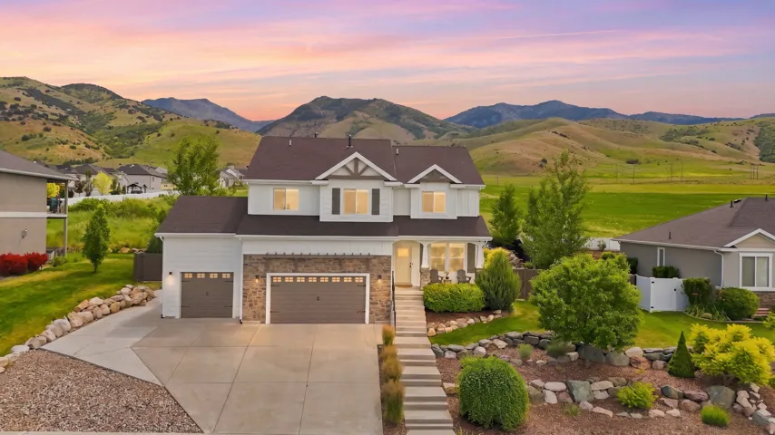 Two-story residence with a stone and siding exterior, a multi-car driveway, and a terraced front yard