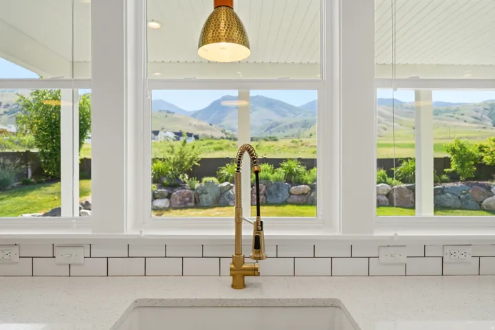 Kitchen sink area featuring a gold-tone faucet, white subway tile backsplash, and light-toned countertop