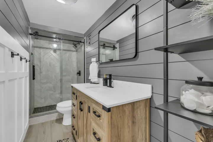 Contemporary bathroom featuring a light wood-finish vanity with a white countertop and matte black hardware