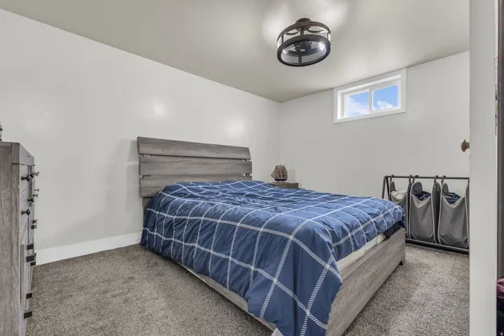 Neutral-toned bedroom featuring a compact window, recessed lighting, and soft gray carpeting