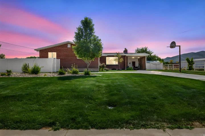 Brick exterior residence featuring a carport, mature tree, and a concrete driveway