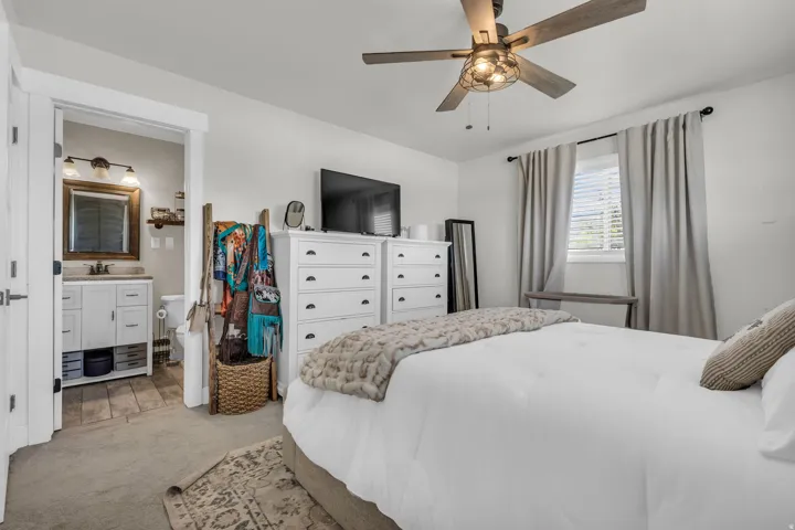 Bedroom featuring carpet flooring, a ceiling fan with light fixture, and a window with blinds and drapery